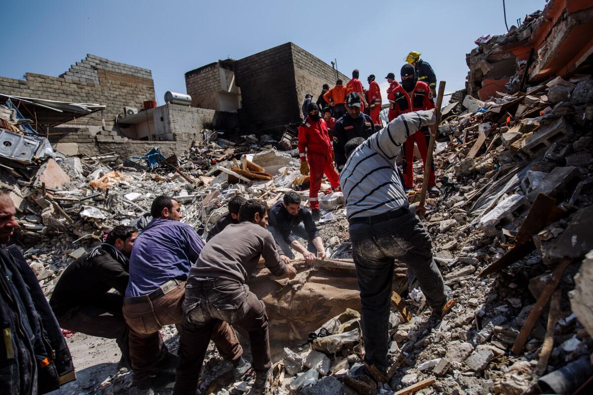Residents of west Mosul’s Jadidah neighborhood help Iraqi civil defense workers retrieve bodies from a home destroyed by an airstrike last month that the coalition is investigating.