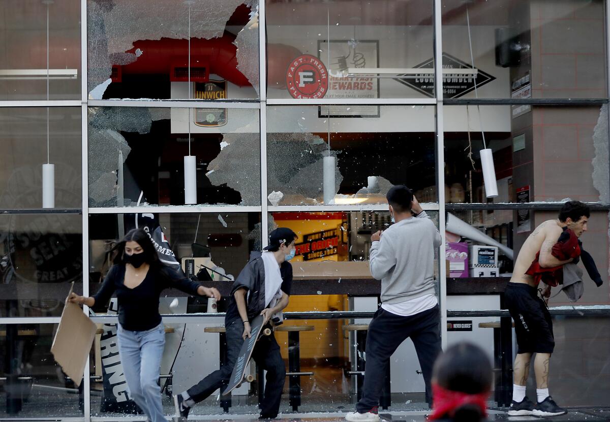 Protesters smash windows along Figueroa Street in downtown Los Angeles on Saturday. 