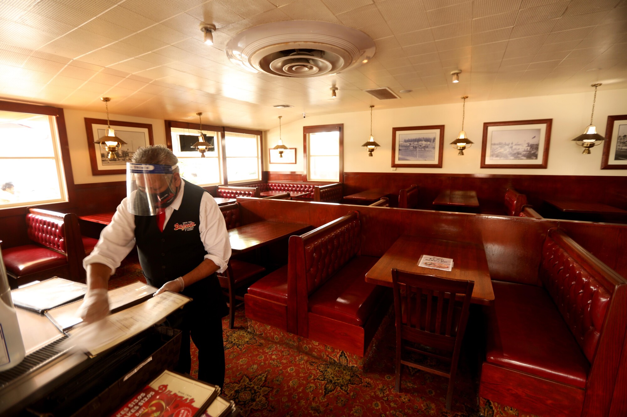 Pedro Armenta cleans menus at Du-par’s restaurant at the Original Farmers Market in Los Angeles.