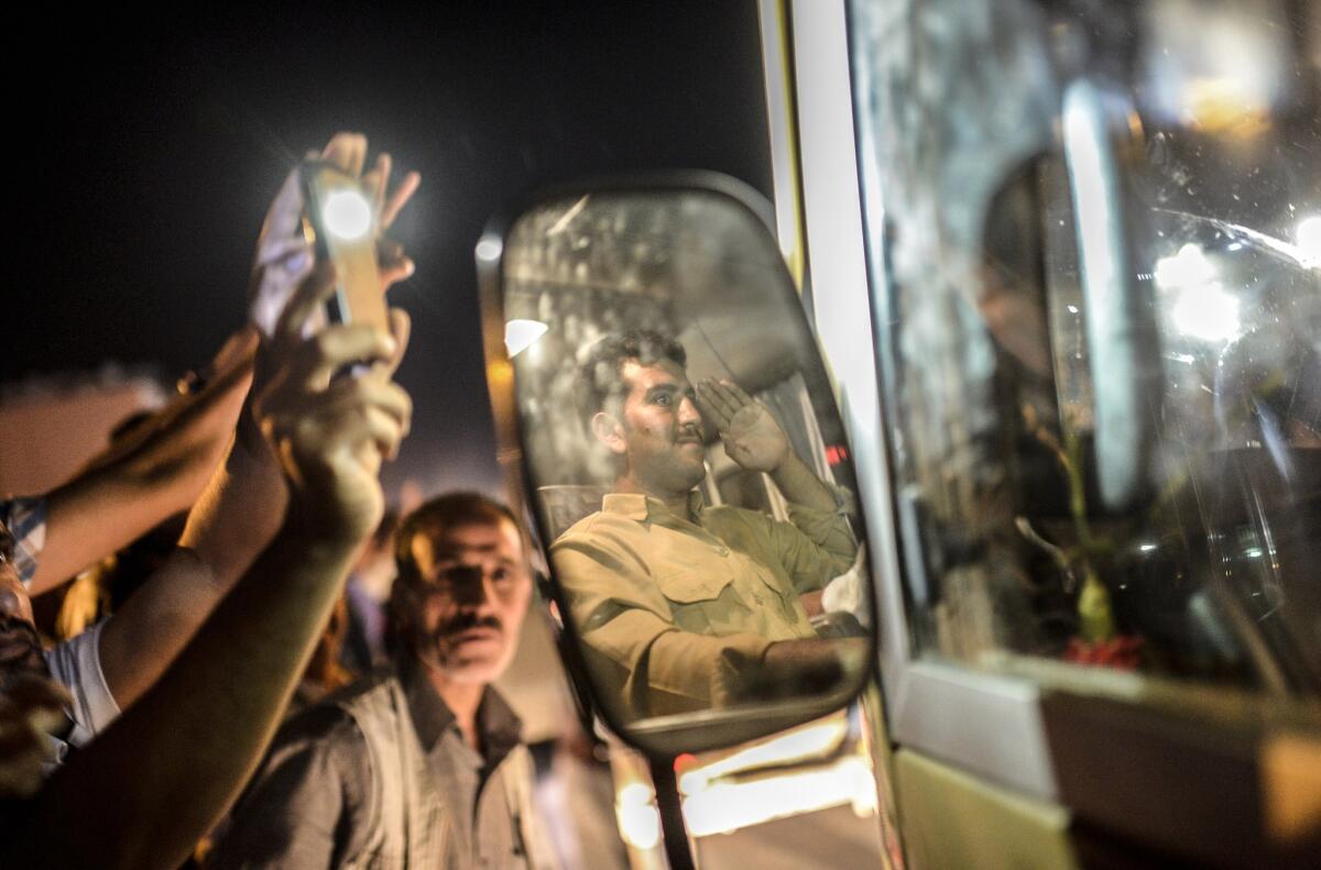 Kurds in Viransehir, Turkey, wave as a peshmerga fighter headed for the Syrian border town of Kobani salutes on Oct. 29.