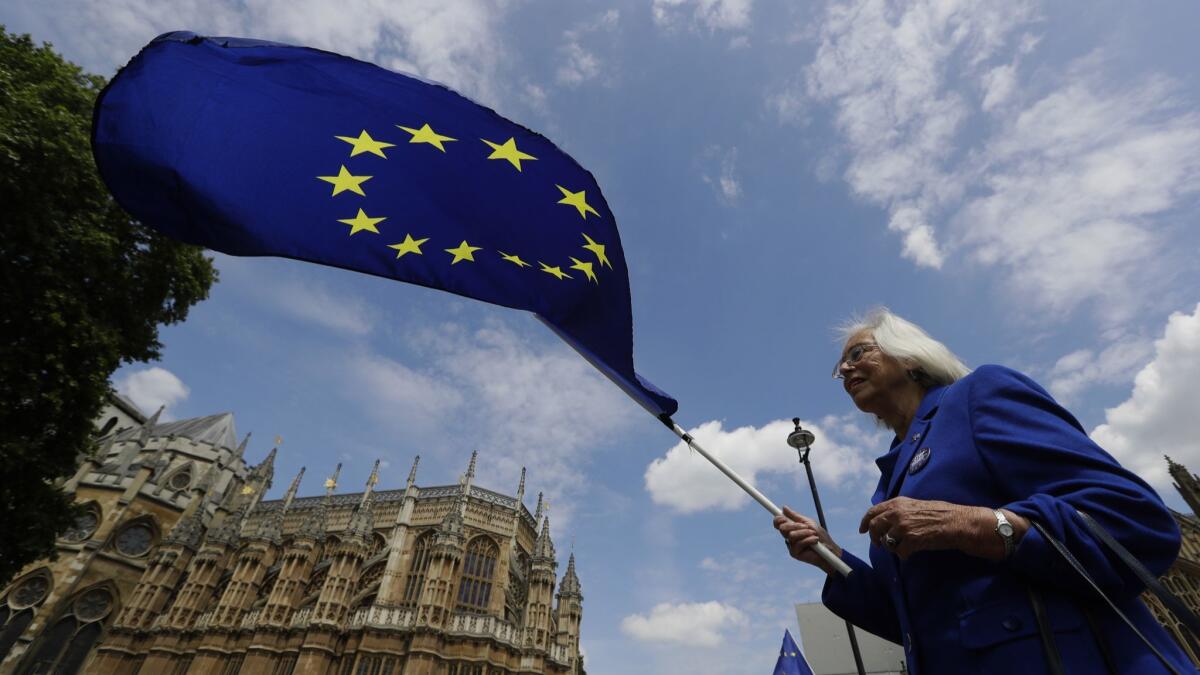 A pro-EU demonstrator waves a flag outside Parliament in London on Wednesday. The British government is bracing for more bruising debate on its key Brexit bill after being forced to give ground to pro-EU lawmakers to avoid defeat.