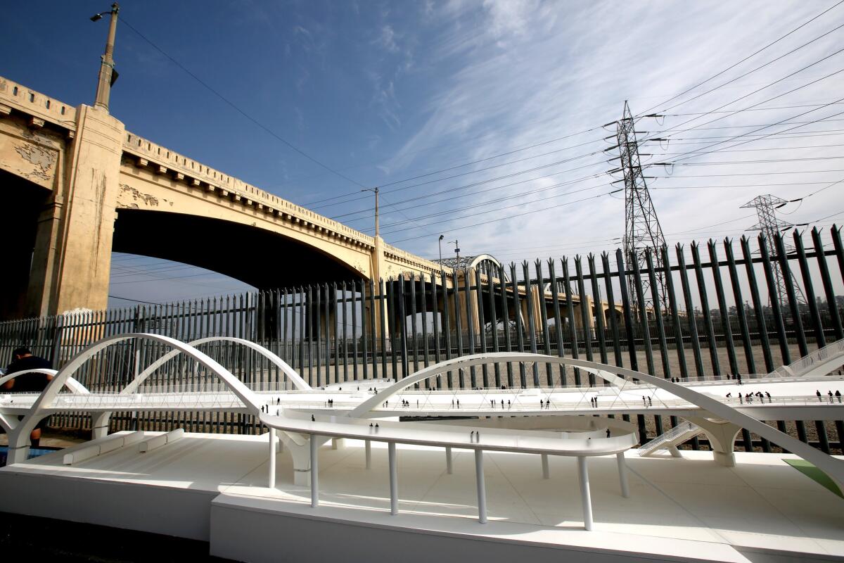 A model of the new viaduct sits near the current bridge, which spans the Los Angeles River. The old bridge stands as a nostalgic wreck. Wooden planks span broken balustrades. Graffiti tags mark the high iron arches. Pigeons befoul the crevices.