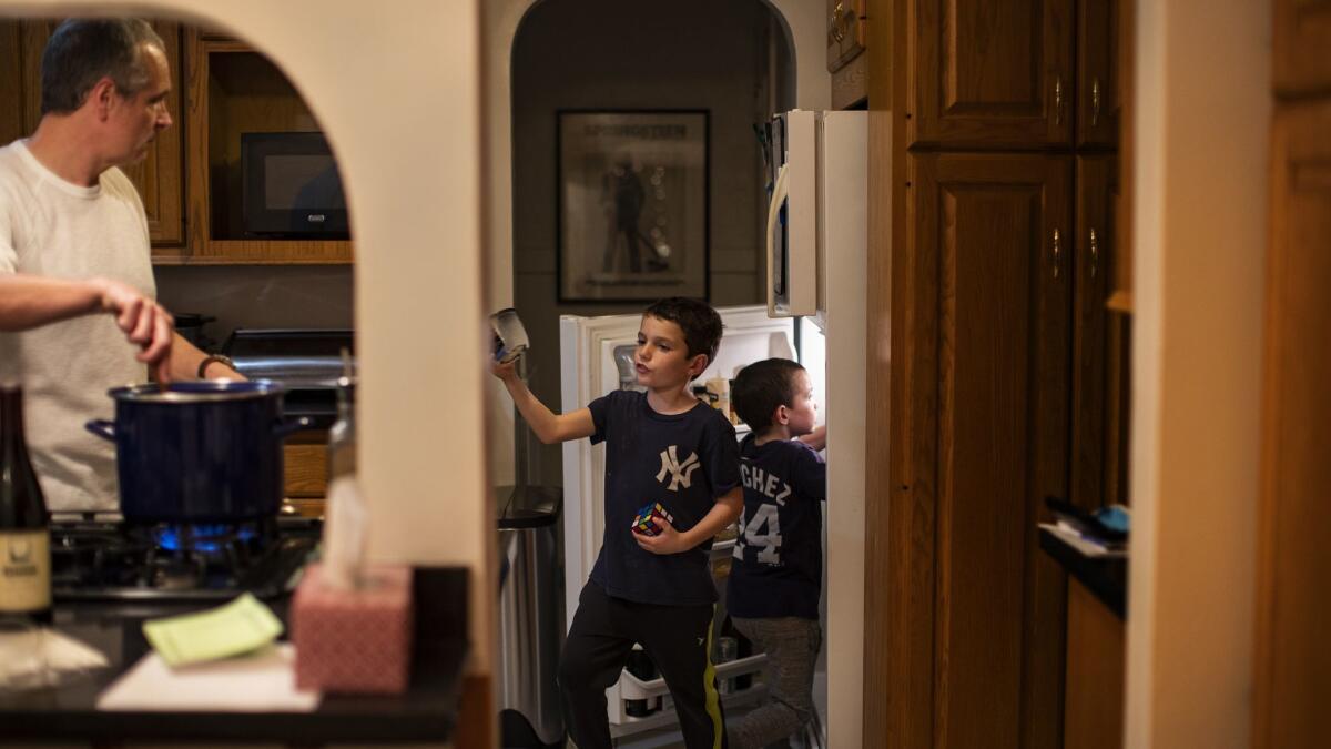 Seven-year-old twins Tom, middle, and Mal Urcioli help their dad, Paul, make dinner. Paul and his wife, Sasha Smith, moved from New York to Los Angeles in 2016.