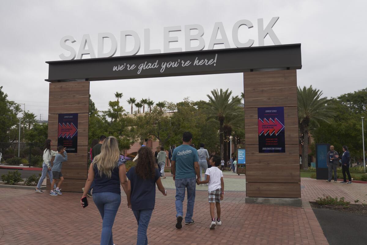 People walk under an entryway that says "Saddleback: We're glad you're here!"
