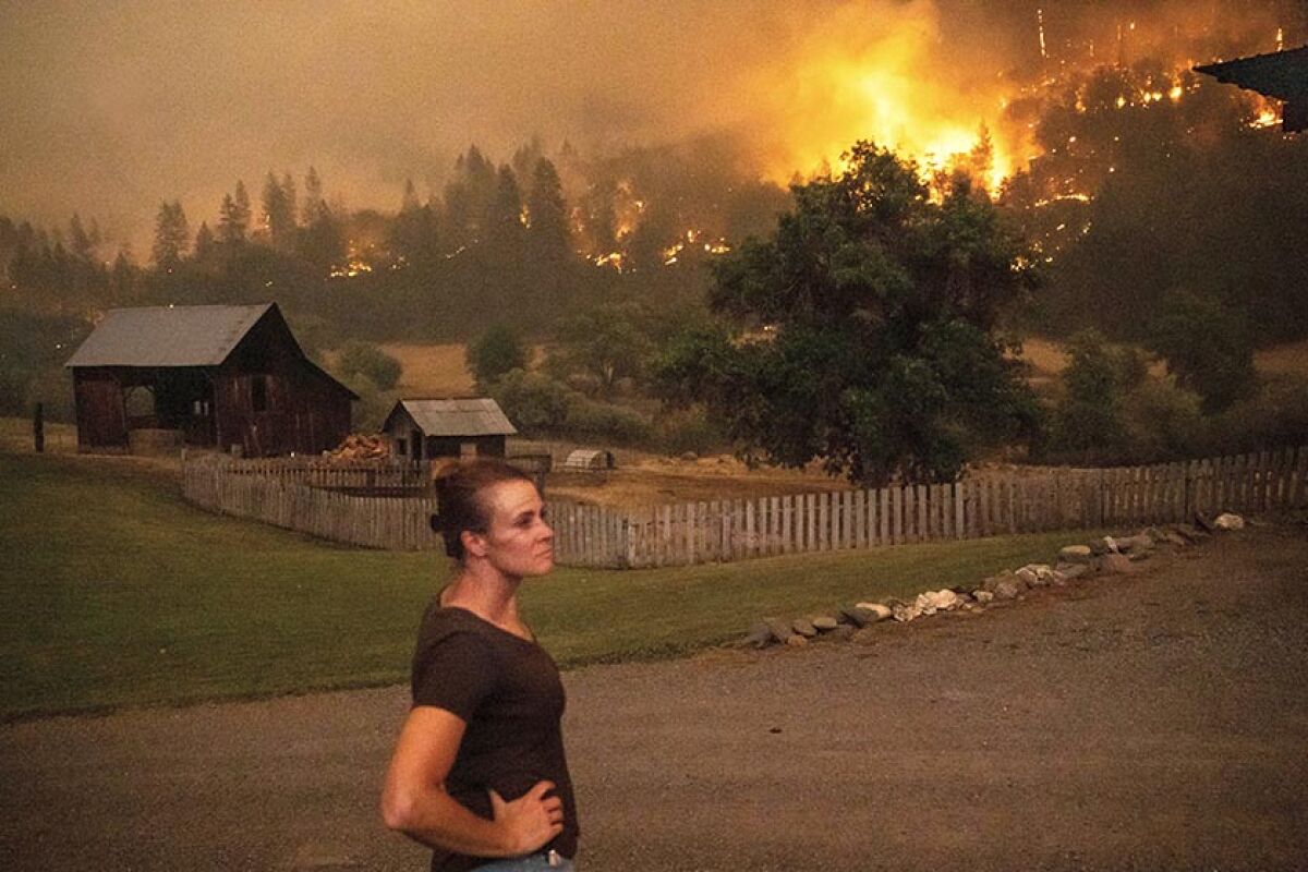 Angela Crawford watches the McKinney fire in trees behind buildings.