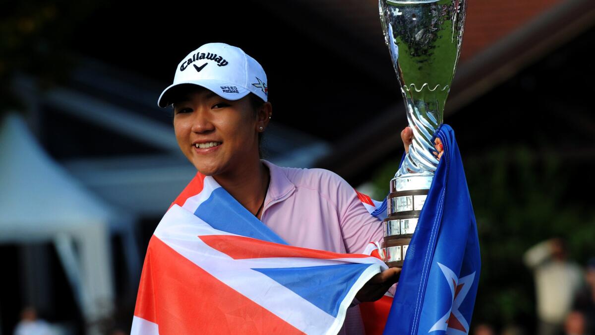Lydia Ko poses with her trophy while wrapped in the flag of New Zealand after winning the Evan Championship on Sunday.