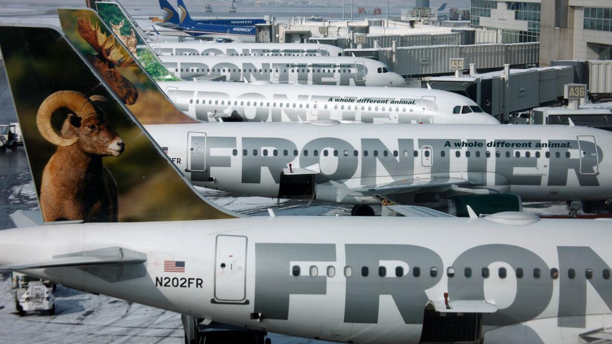 Frontier Airlines jetliners sit stacked up at gates at Denver International Airport.