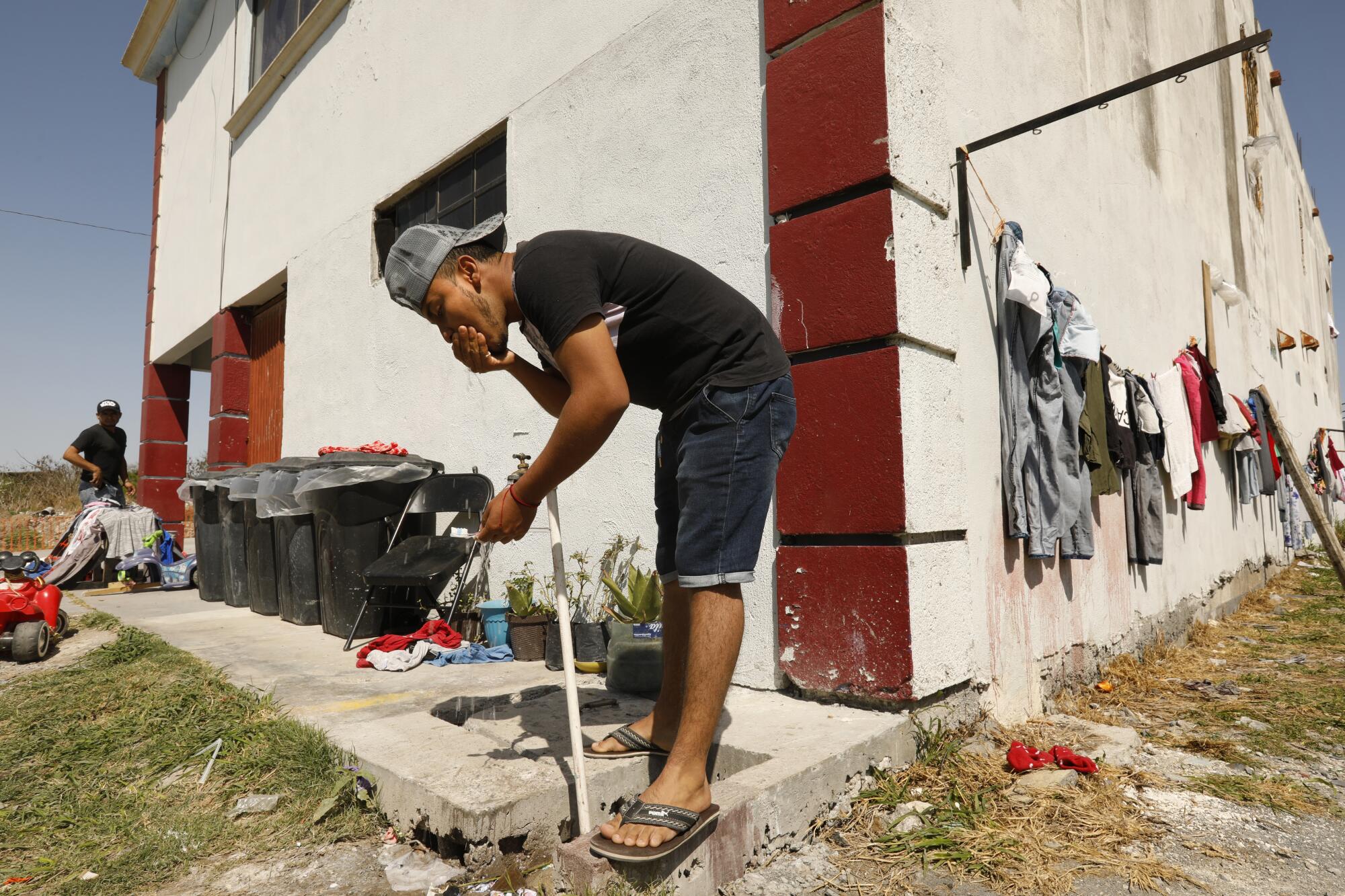 A migrant draws water from an outdoor faucet.