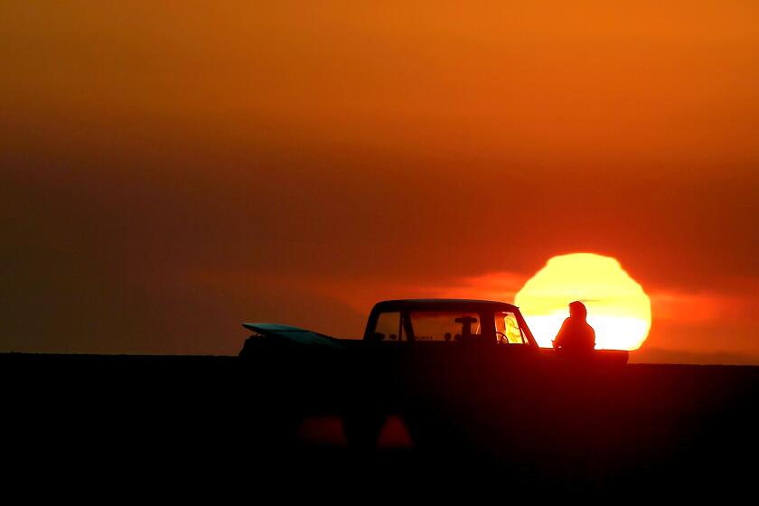 HUNTINGTON BEACH, CA. - DEC. 2, 2020. A surfer takes in the sunset at Bolsa Chica State Beach on Tuesday, Dec. 2, 2020. Warm, dry weather is forecast for the rest of the week, with the possiility of strong Santa Ana winds elevating the possibility of wildfires. (Luis Sinco/Los Angeles Times)