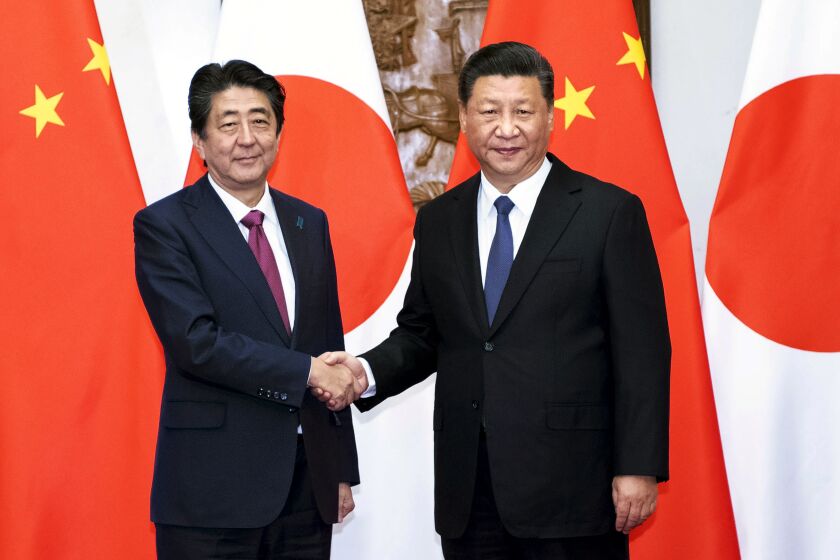 FILE - In this photo released by Xinhua News Agency, Japanese Prime Minister Shinzo Abe, left, shakes hands with Chinese President Xi Jinping as they pose for photographers before a meeting at the Diaoyutai State Guesthouse in Beijing on Oct. 26, 2018. Thursday, Sept. 29, 2022, marks the 50th anniversary of the historic communique that former Japanese Prime Minister Kakuei Tanaka signed with former Chinese Premier Zhou Enlai. (Li Tao/Xinhua via AP, File)