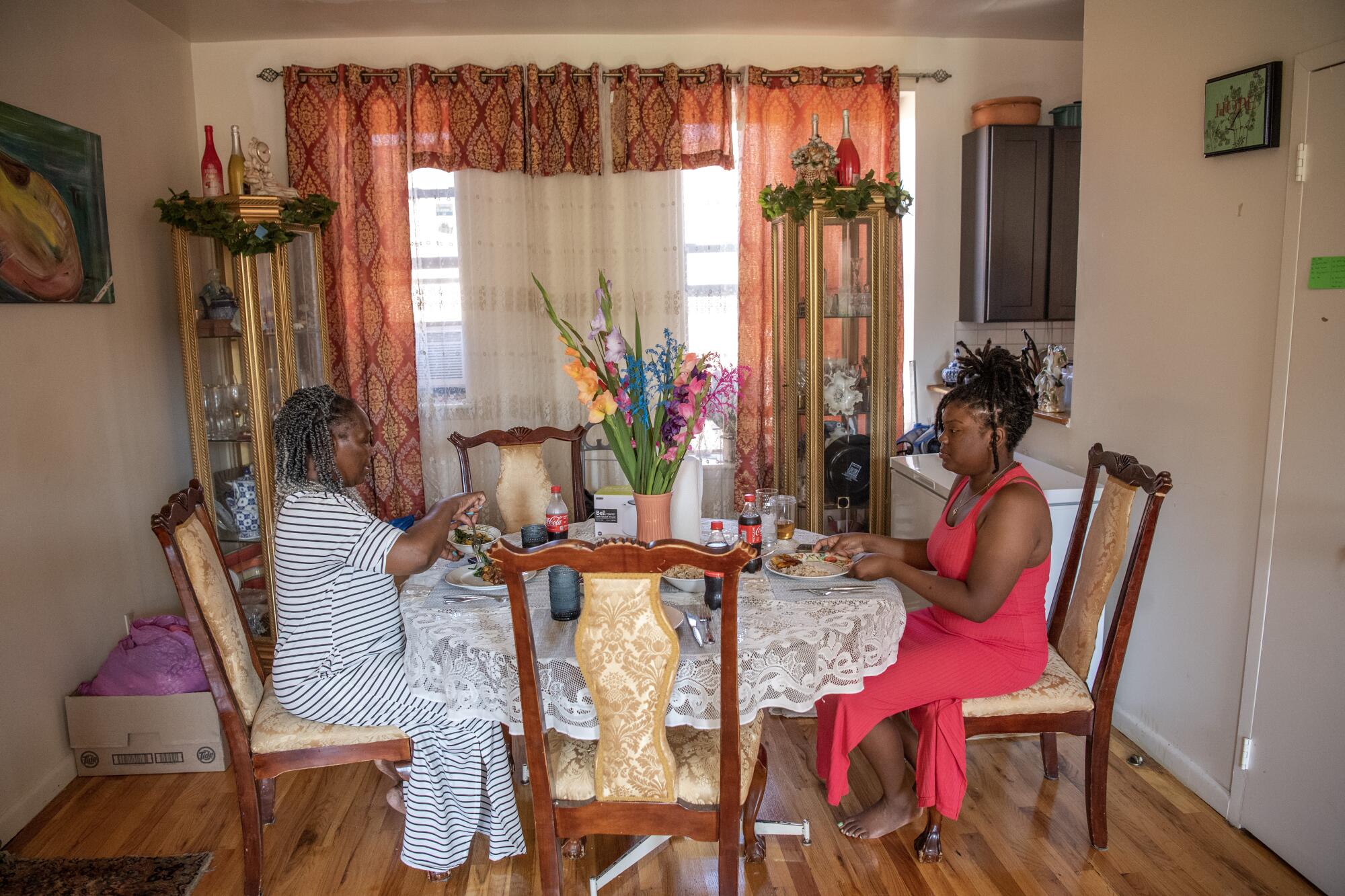 Two women eating at a dining room table decorated with a bouquet of fresh flowers