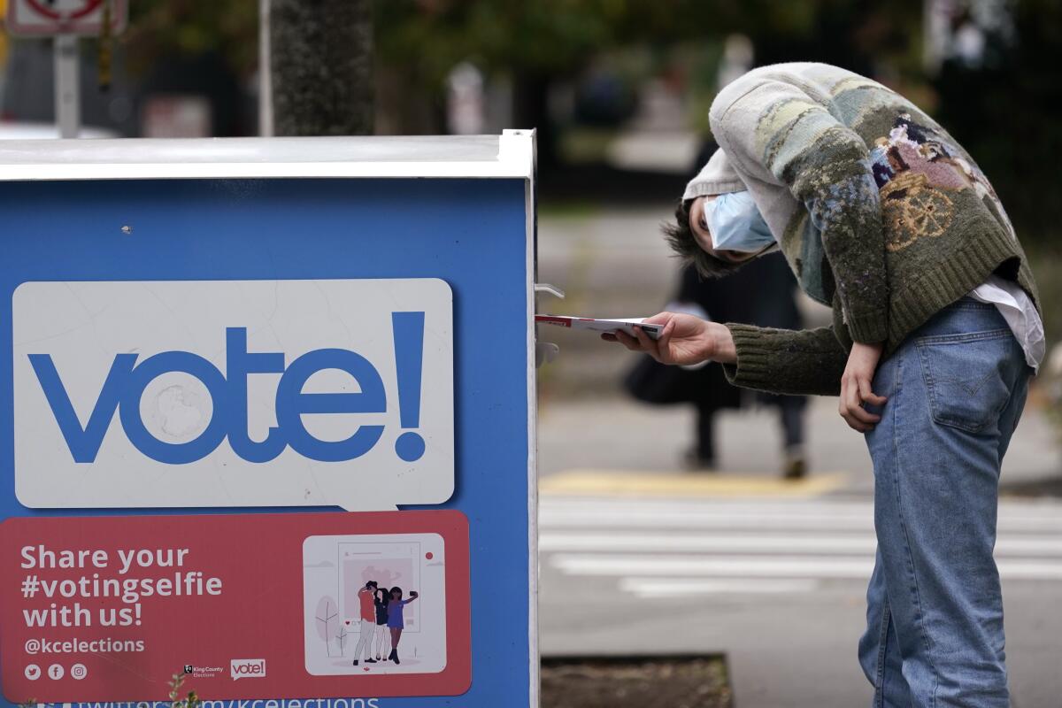 A voter places his ballot inside a drop box in Seattle on Oct. 28, 2020.
