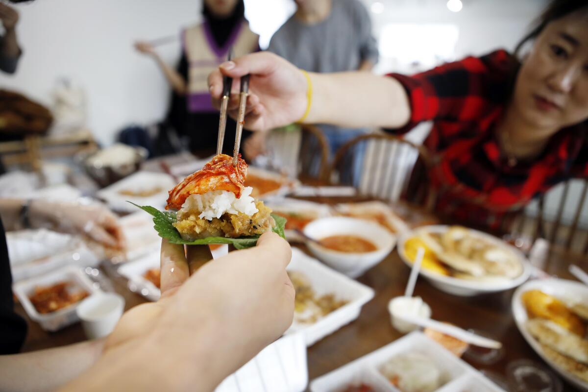 Students taste the completed kimchi atop steamed pork after Jessie Kim's cooking class in November.