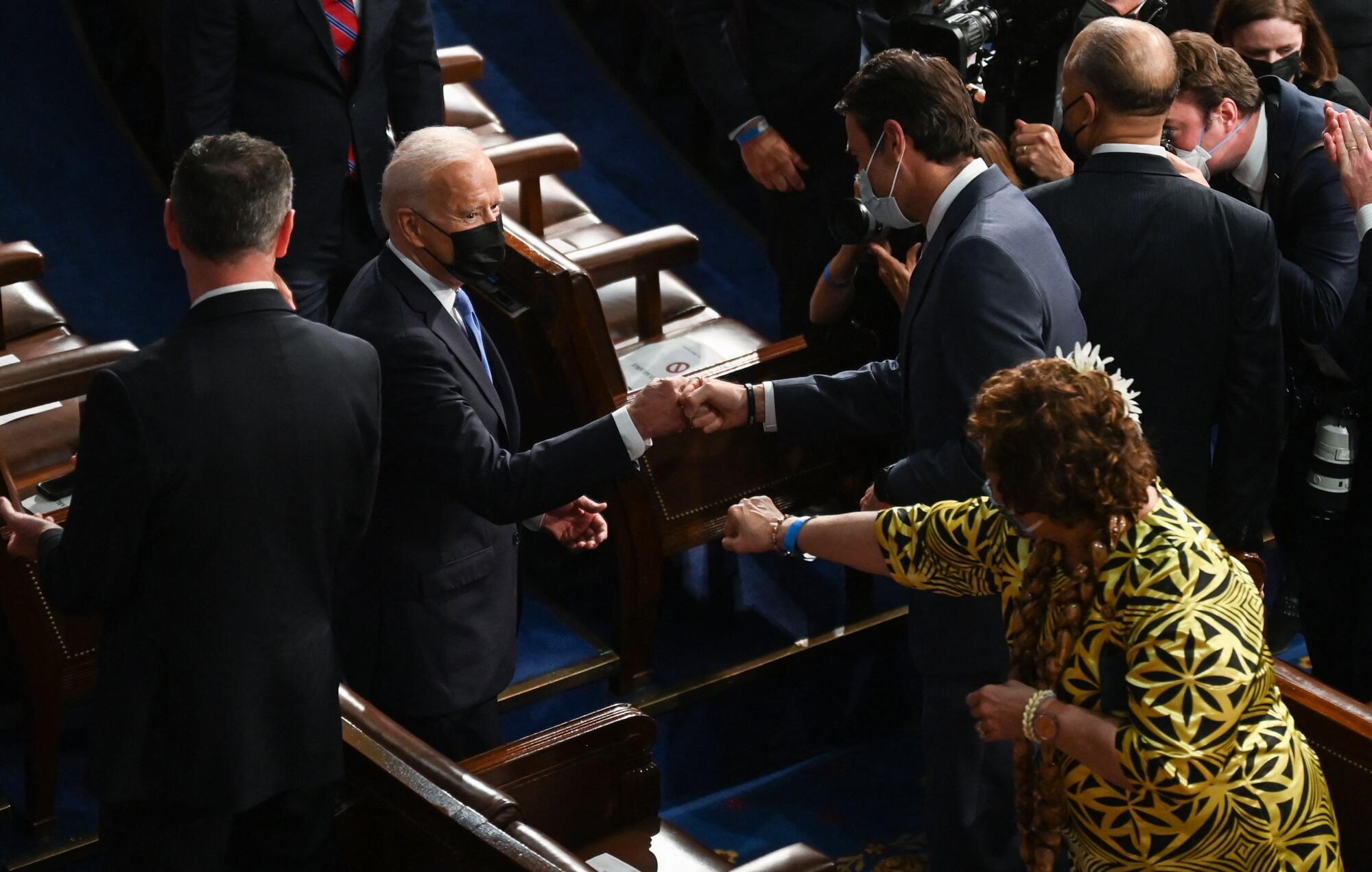 Two men bump fists and a woman reaches out her fist toward them.