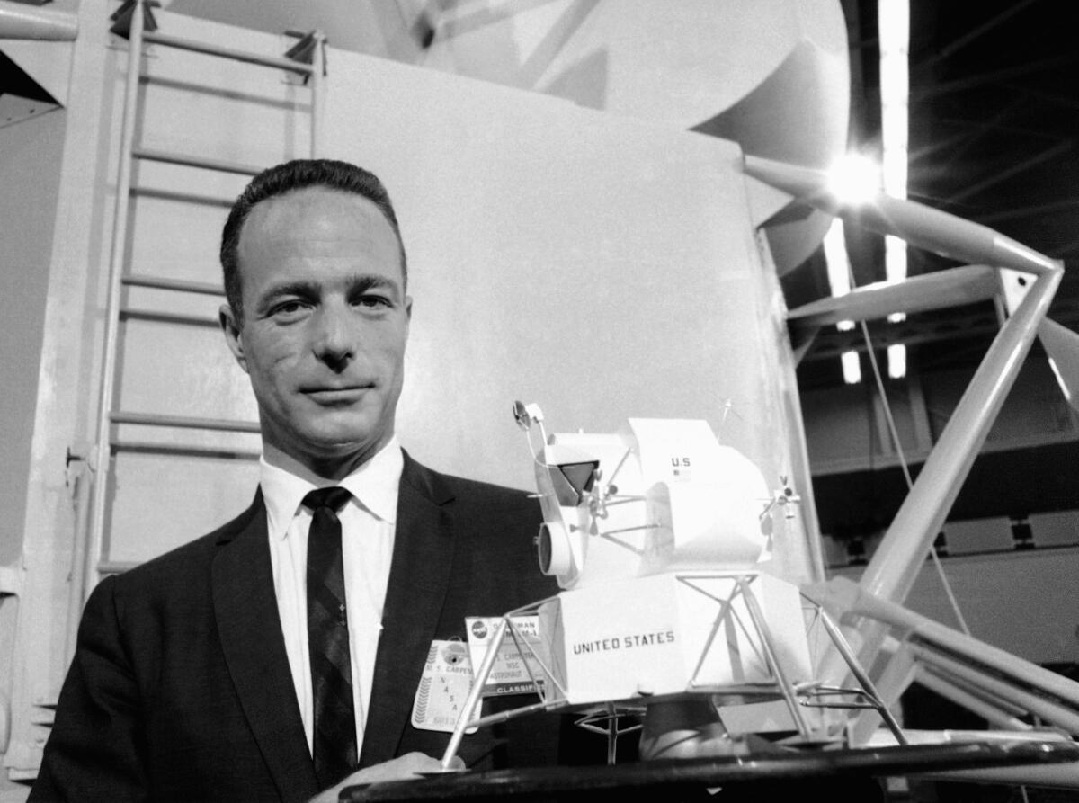 Astronaut Scott Carpenter poses with a model of the Lunar Excursion Module at the Grumman Aircraft Engineering Corp. plant in Bethpage, N.Y. Carpenter, the second American to orbit the Earth, died Thursday after a stroke. He was 88.