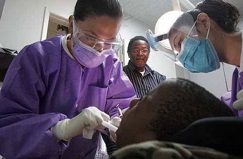 Dr. Diana Zschaschel, left, and her assistant Ada Palacios treat 13-year-old Vergery Grubbs Jr., who has cerebral palsy, as his father, Vergery Grubbs Sr., watches. Zschaschel accepts patients with disabilities, who many dentists won't treat.