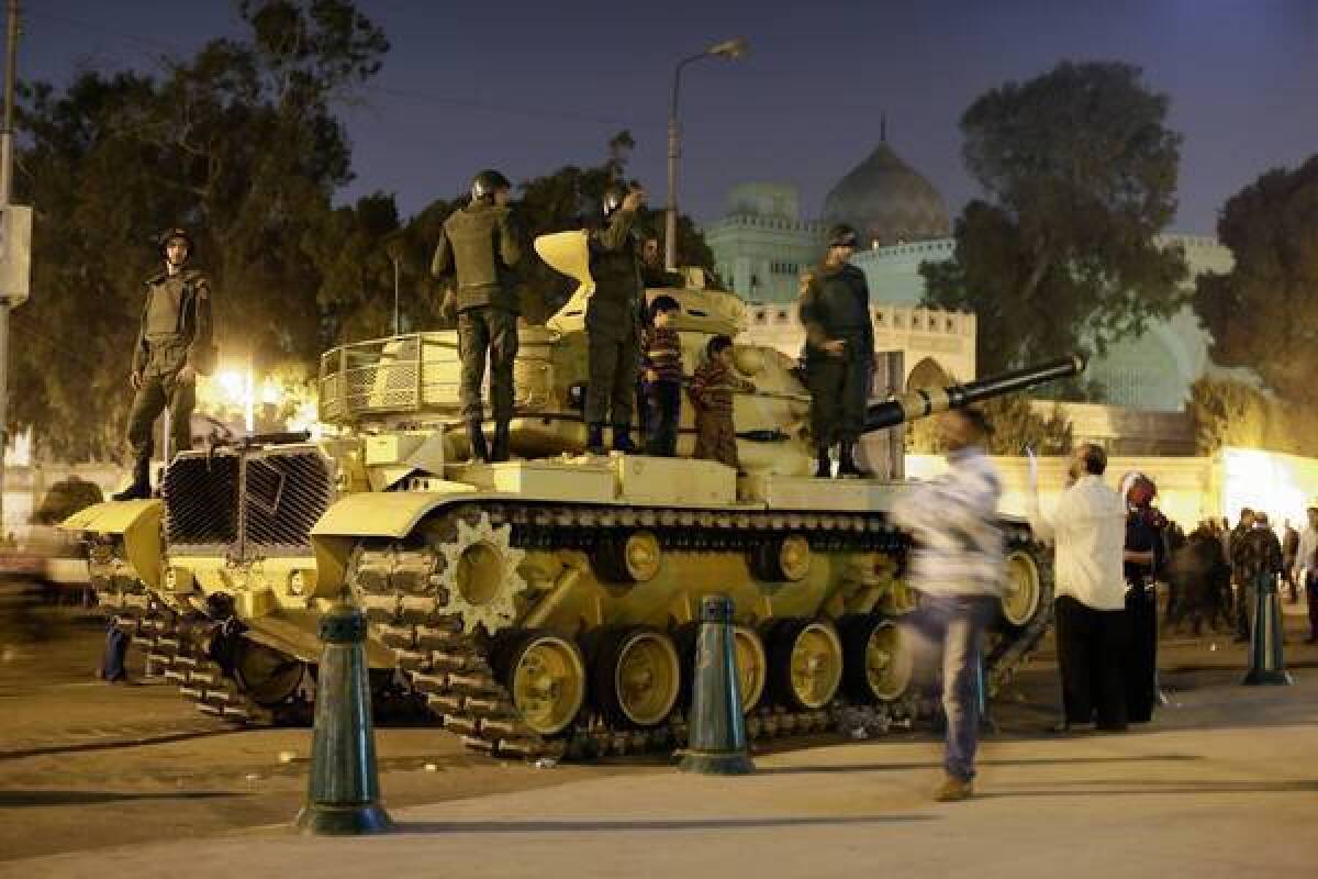 A protester takes a photo of his children next to soldiers atop an army tank Saturday outside the presidential palace in Cairo, Egypt.