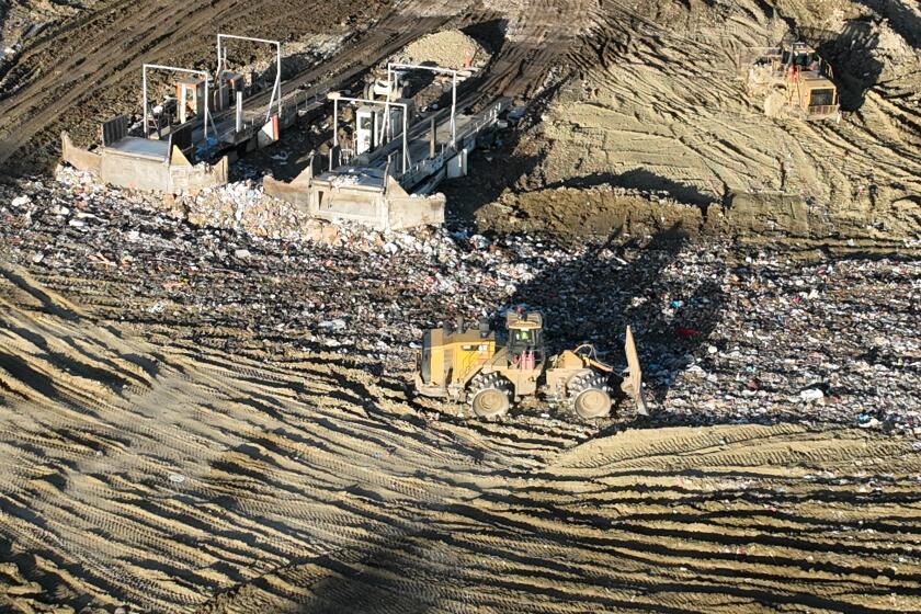 Castaic, CA - February 22: An aerial view of trucks unloading, heavy equipment spreading trash over a hill near where 100 metal storage containers storing contaminated or polluted water, holding up to 20,000 gallons each as the result of an underground landfill fire at Chiquita Canyon Landfill in Castaic Thursday, Feb. 22, 2024. Around 200,000 gallons of the contaminated water is coming out of the landfill each day. Environmental regulators have found elevated levels of cancer causing Benzine in the polluted water spilling onto the surface of the landfill. Landfill operators are also constructing a drainage system to capture the contaminated water that is spilling onto the surface and proactively pumping the water. Residents of Val Verde and Castaic are protesting to call for Chiquita Canyon Landfill to be closed in Hasley Canyon Park in Castaic. Garbage has been burning deep inside the landfill due to a chemical reaction for much of the past year, and recently scalding-hot contaminated water has surged to the surface. The protest follows calls from the County Supervisor Kathryn Barger's office, which said the landfill should provide funds to relocate residents who want to temporarily move until the issue is resolved. (Allen J. Schaben / Los Angeles Times)