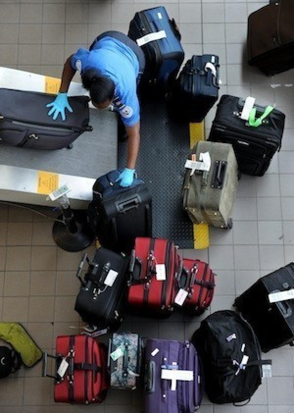 A TSA agent loads luggage onto a belt to be X-rayed at Los Angeles International Airport. Travelers are required to pack liquids more than 3.4 ounces in their checked luggage.