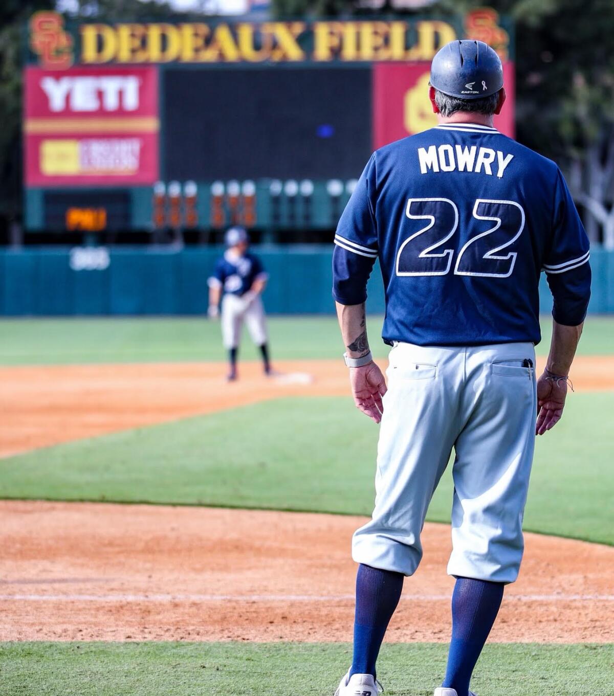 Birmingham coach Matt Mowry is shown watching a Patriots runner at second base from the third-base coaching box.
