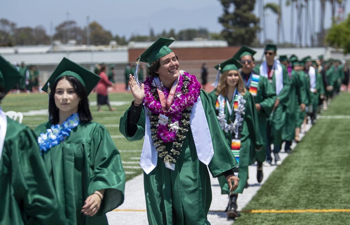 Costa Mesa High graduate Anthony Mark waves to his family Thursday during the school's commencement.