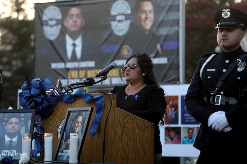 Melissa Valencia stands before a microphone at a lectern in an outdoor setting