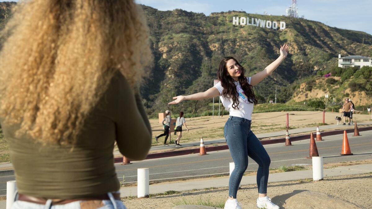 Funda Durdu poses for her friend Ikram Boulganat, both visiting from Germany, below the Hollywood sign on Canyon Lake Drive.