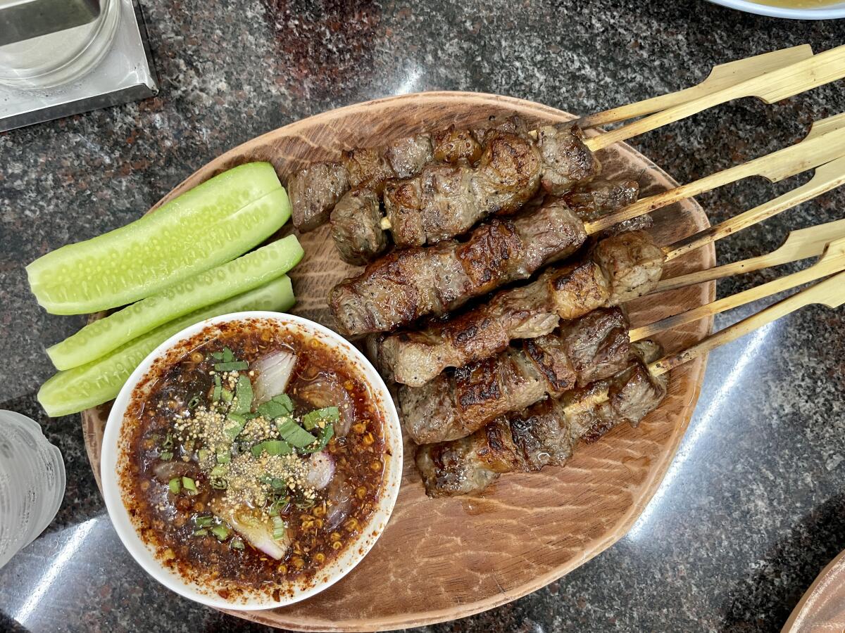 Skewers of grilled pork plus sides on a plate.