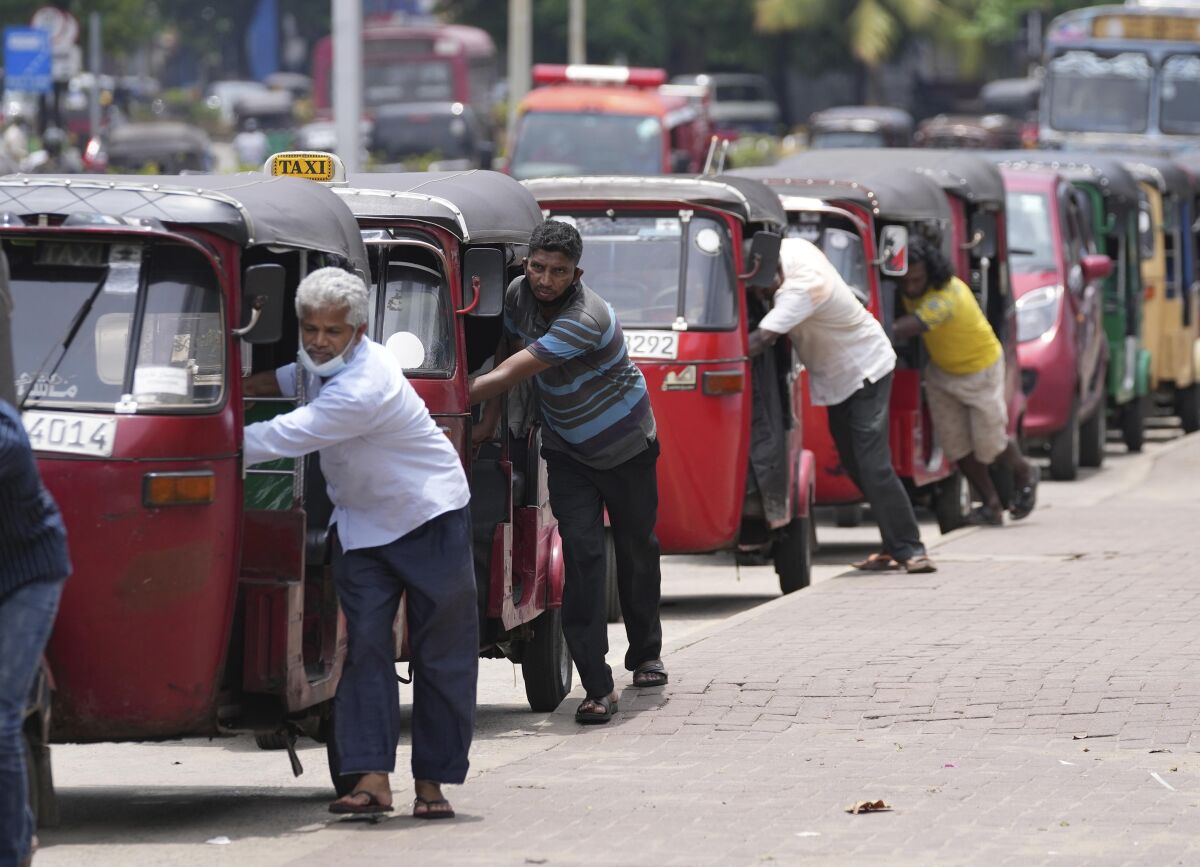 Choferes de minitaxis empujan sus vehículos para comprar gasolina en Colombo (Sri Lanka) 