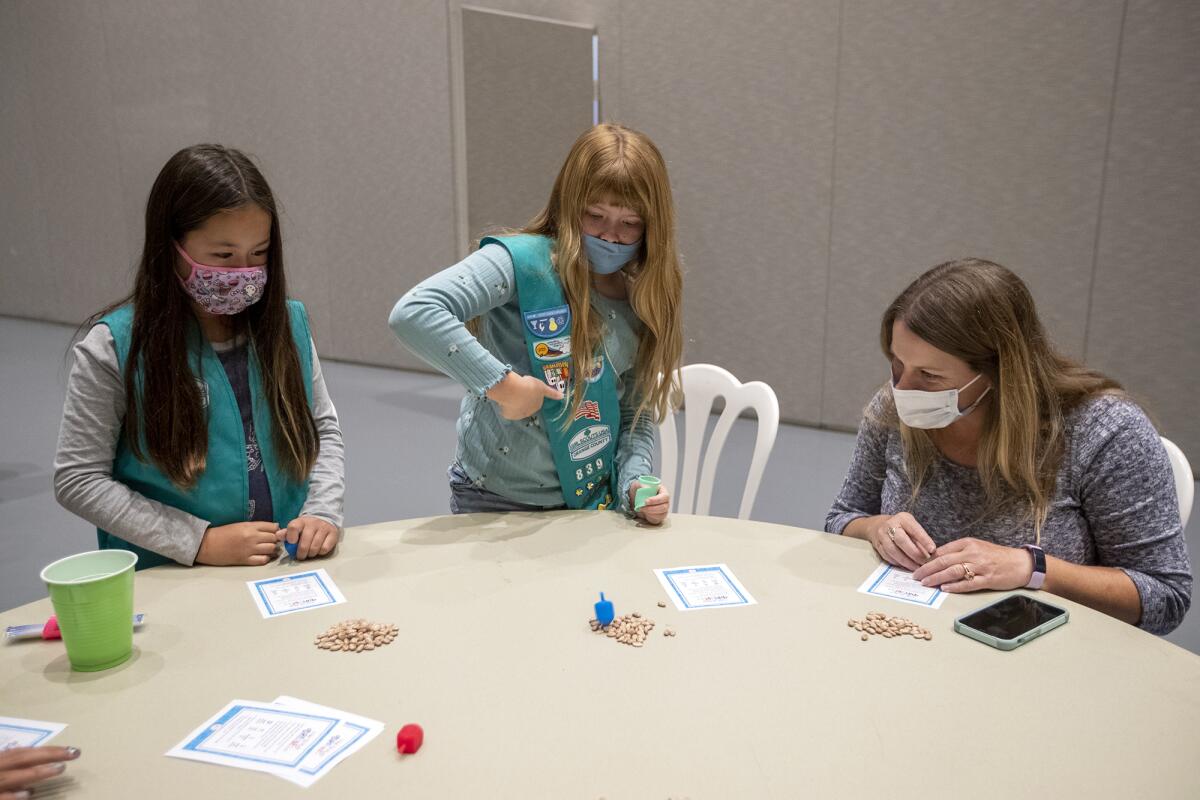 Izzy Kent,Hannah O'Roark and Beth O'Roark with the Girl Scout Troop 8395 play the dreidel game.