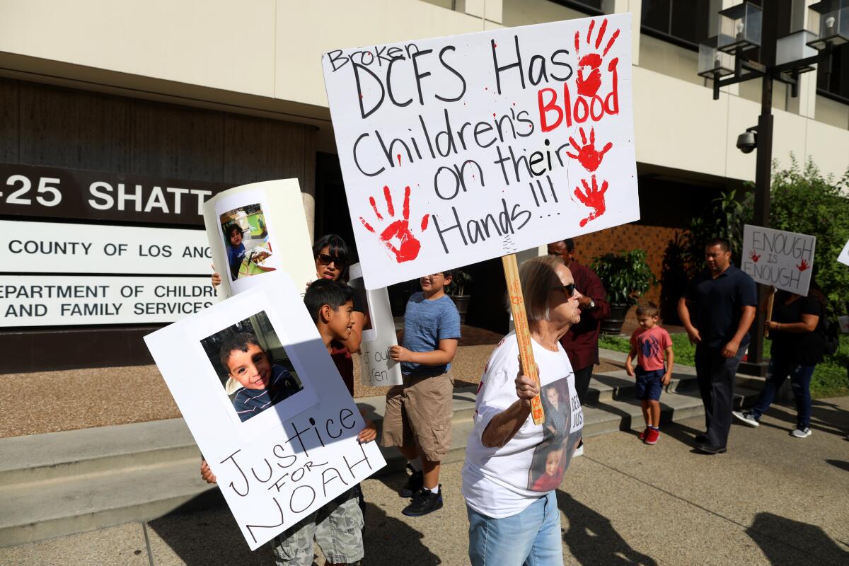 Protesters hold signs reading 'Justice for Noah' and 'DCFS Has Children's Blood on Their Hands'