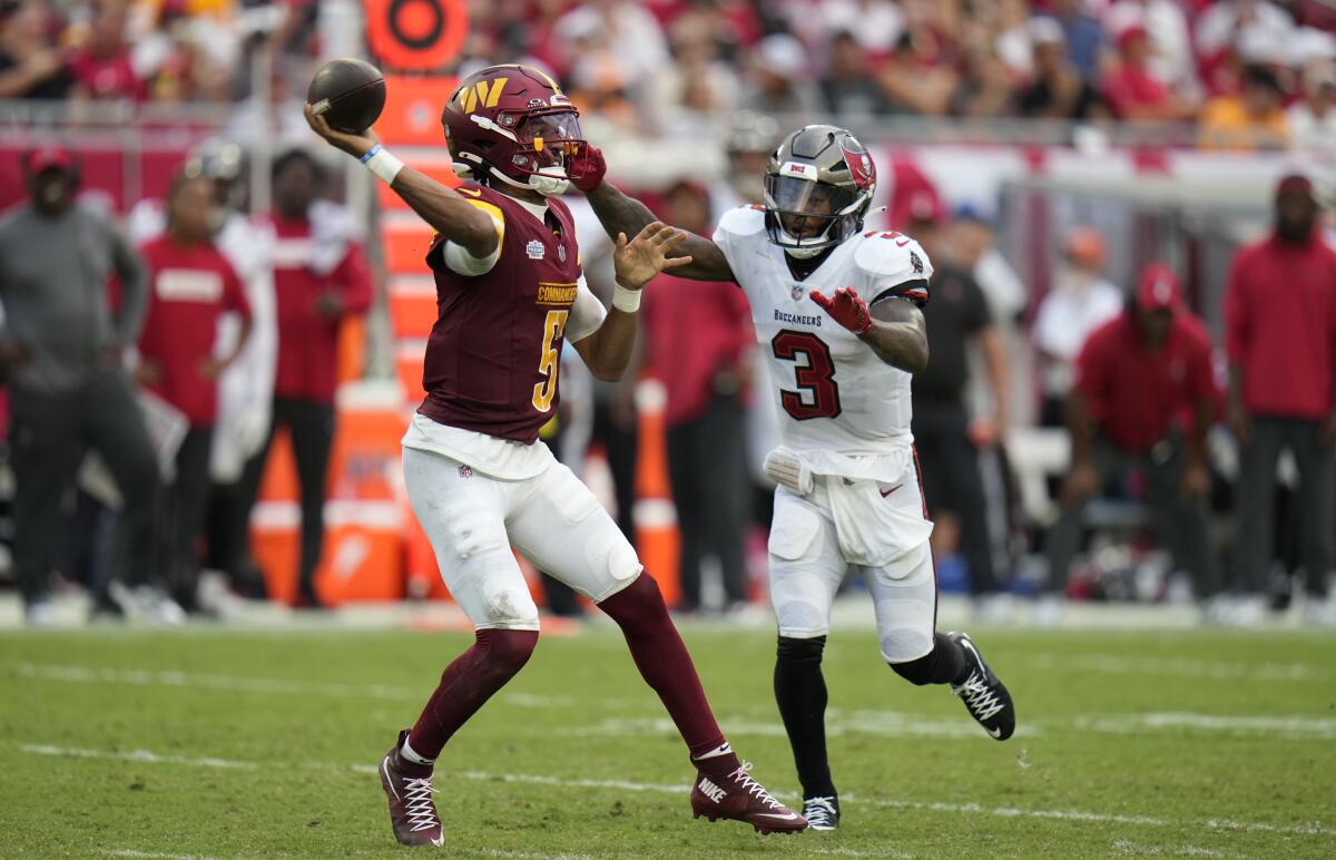 Commanders quarterback Jayden Daniels (5) is pressured by Buccaneers safety Jordan Whitehead (3) as he passes.