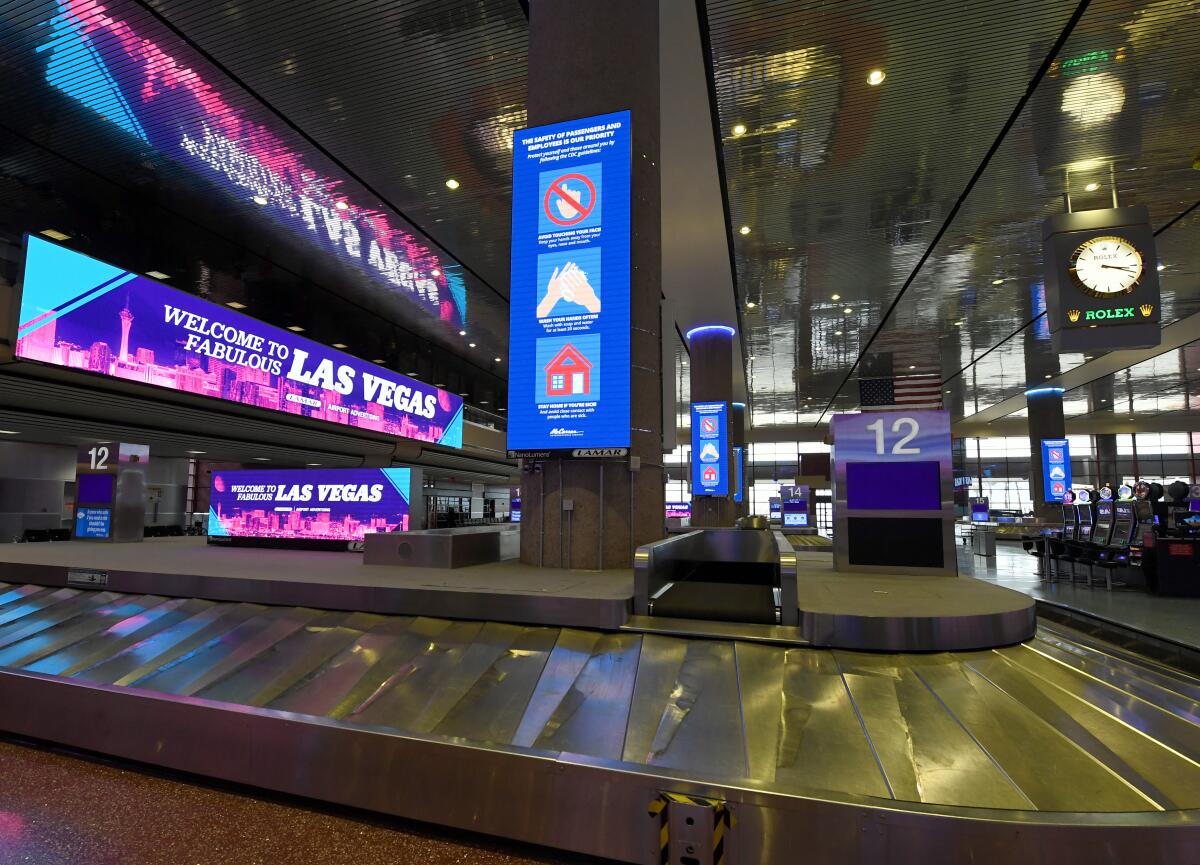 Digital signs in the baggage claim area at McCarran International Airport in Las Vegas display welcome signs and guidelines from the Centers for Disease Control and Prevention on protection from the coronavirus.