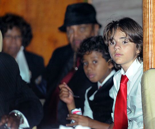 Prince Michael Jackson, far right, with Katherine and Joe Jackson in the background, sits through his father's funeral.