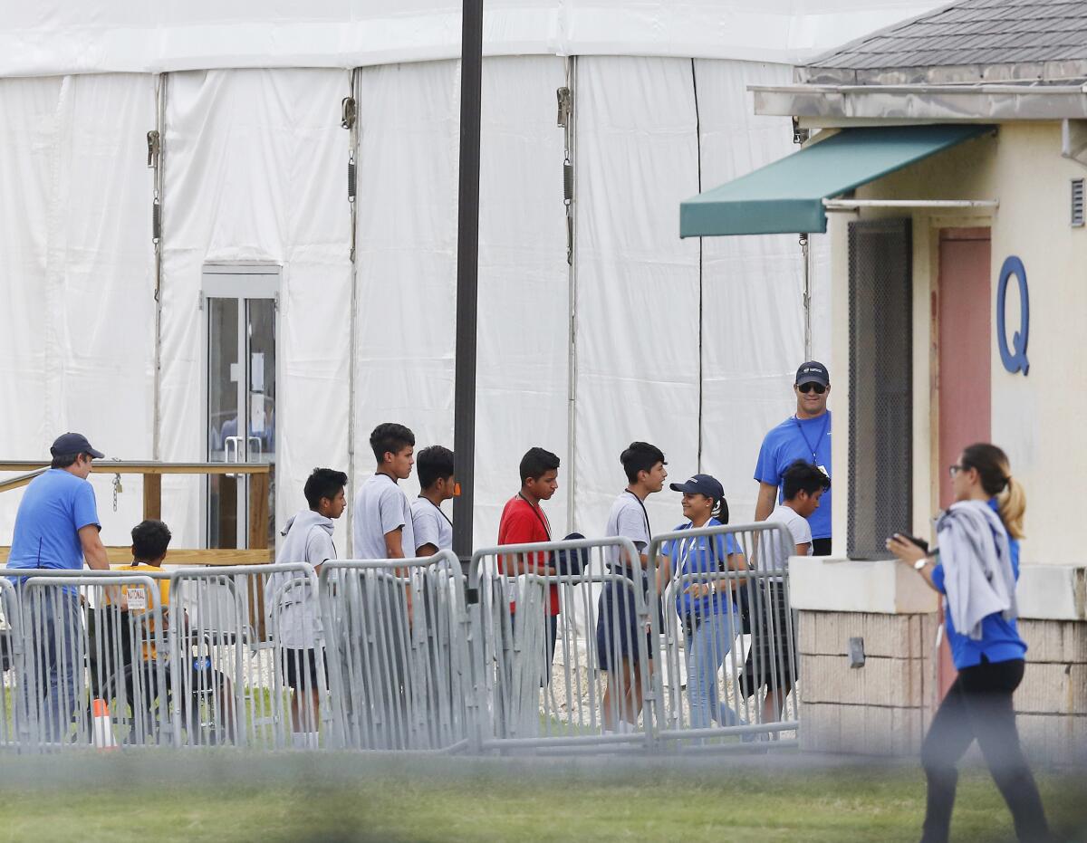 Immigrant children walk in a line outside a shelter 