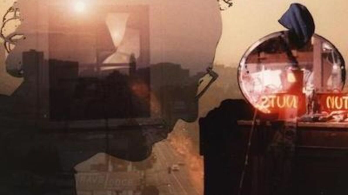 Still image of a man's head with glasses with a highway behind him.
