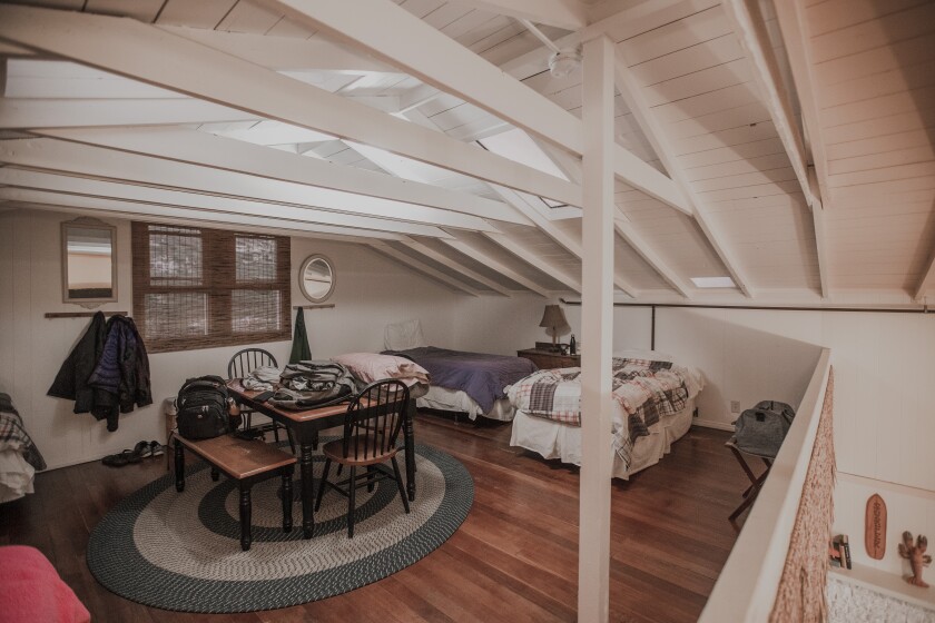 A room in the Long Board Lodge cottage has a bed and a table with four chairs.