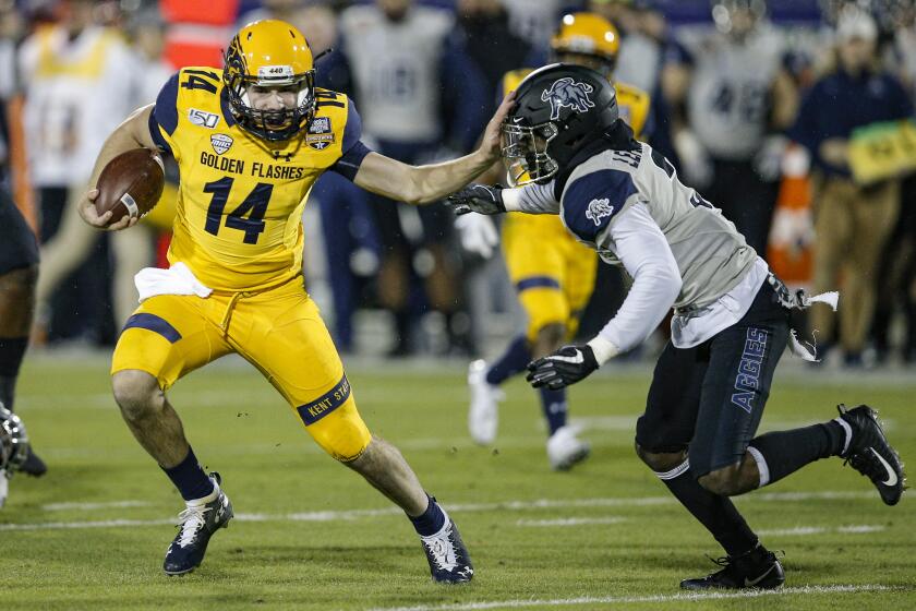 Kent State quarterback Dustin Crum (14) carries the ball as Utah State safety Troy Lefeged Jr. (3) defends during the first half of the Frisco Bowl NCAA college football game Friday, Dec. 20, 2019, in Frisco, Texas. (AP Photo/Brandon Wade)