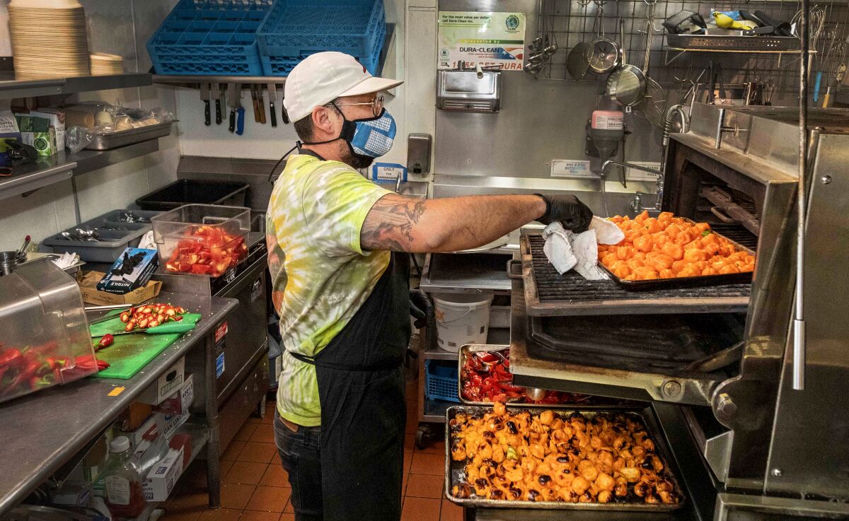 A chef puts a tray of chiles in an oven