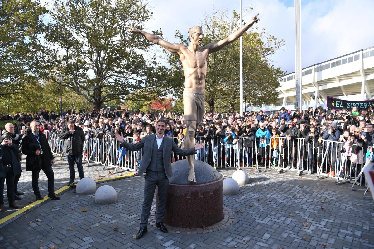 La estrella del Galaxy, Zlatan Ibrahimovic, posa en frente de su estatua de bronce a su semejanza durante una ceremonia de develación en Malmo, Suecia.