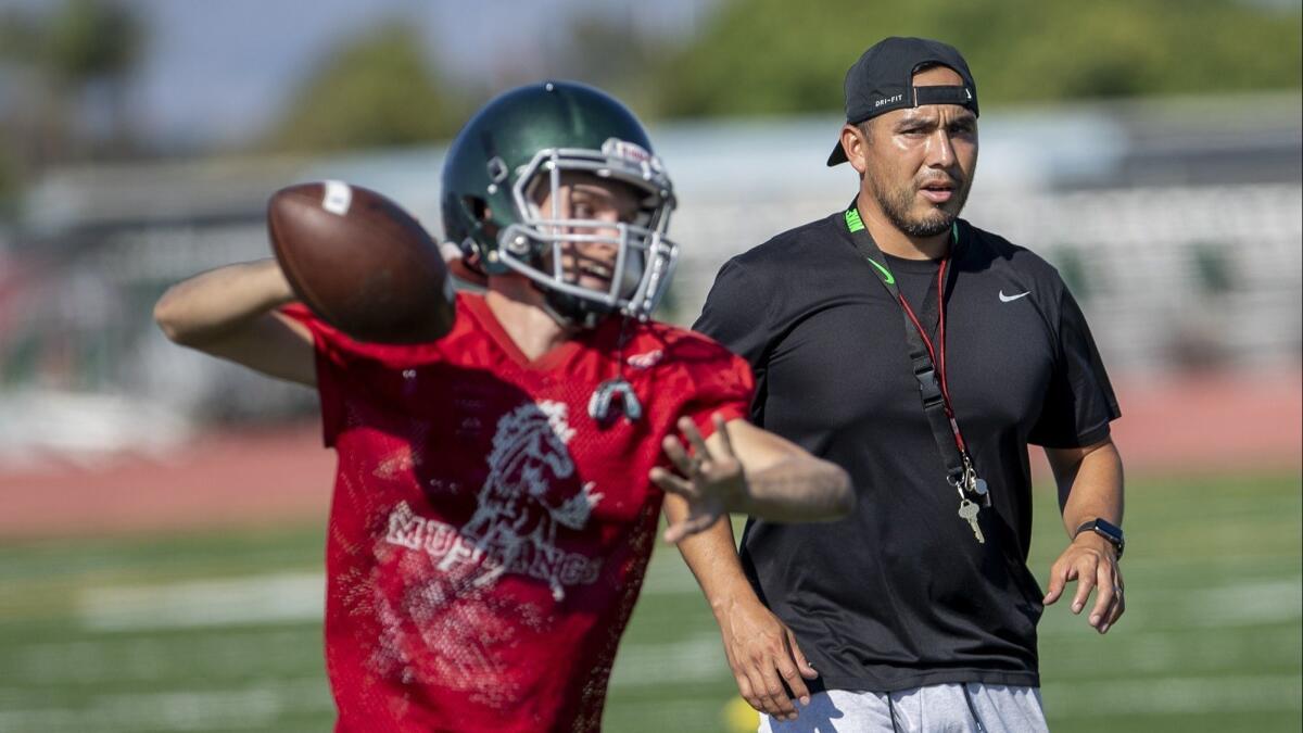 Costa Mesa High coach David Gutierrez works with quarterback Blake Juncker during practice on Aug. 14. Juncker returned to the program for his senior year after not playing last season.