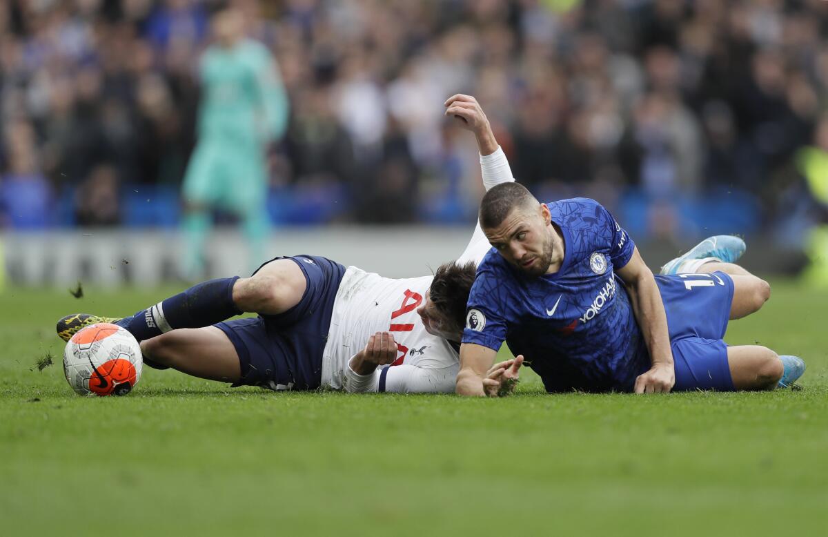 Chelsea's Mateo Kovacic eyes the ball after falling while fighting for it with Tottenham Hotspur's Giovani Lo Celso during their English Premier League soccer match in London, England, Saturday, Feb. 22, 2020. (AP Photo/Kirsty Wigglesworth)