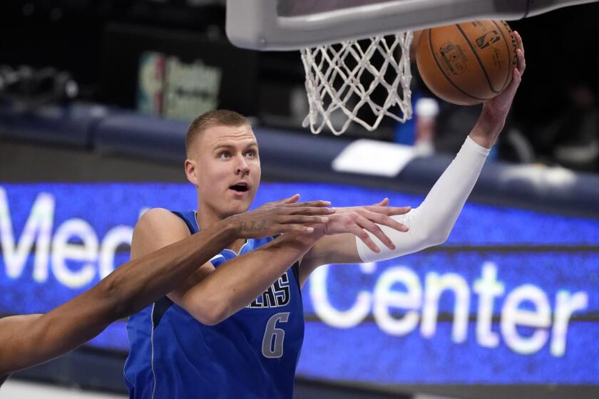 San Antonio Spurs forward Rudy Gay, left,defends against a shot by Dallas Mavericks center Kristaps Porzingi.