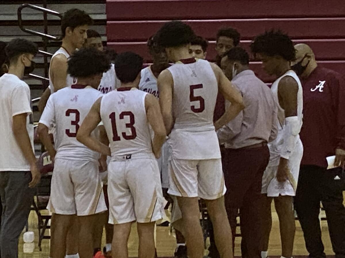 Alemany players gather around coach Tray Meeks during a timeout.