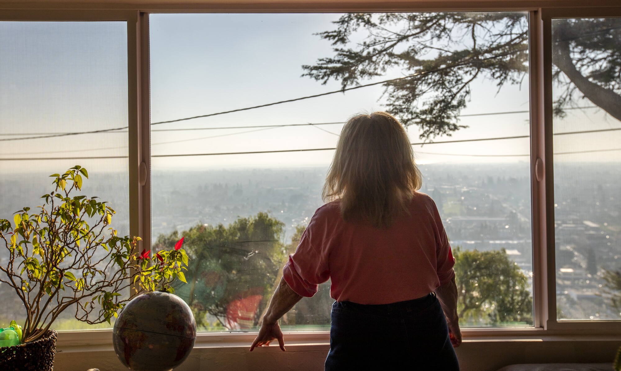 Debbie Frederick looks out her living room window in Hayward. On a clear day, she can see San Francisco Bay. 