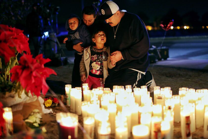 The Arias family kids, Junior, 2, left and Jenesis, 5, bottom, and their parents, Robert and Sierra pay their respects at a memorial site in San Bernardino, Calif.