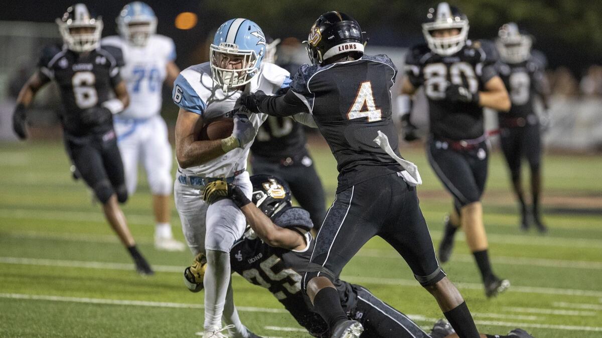 Corona del Mar High's John Humphreys is wrapped up by JSerra's Anthony Ward (25) and Tarik Luckett (4) during a game on Friday.