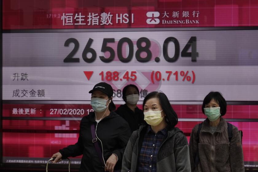 People walk past an electronic board showing Hong Kong share index outside a local bank in Hong Kong, Thursday, Feb. 27, 2020. Shares fell in Asia on Thursday after President Donald Trump announced the U.S. was stepping up its efforts to combat the virus outbreak that began in China. (AP Photo/Kin Cheung)