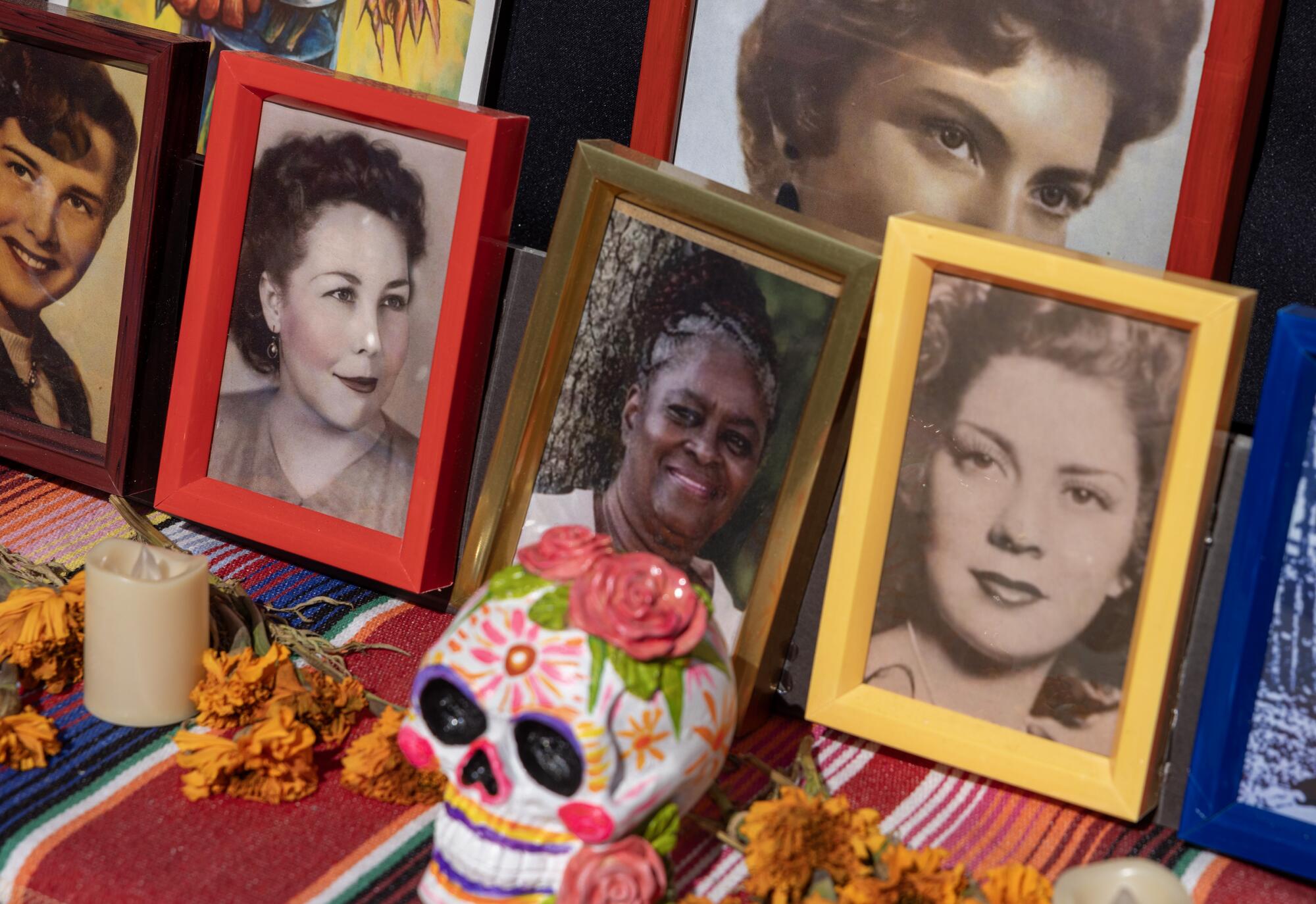 Pictures of loved ones rest on an altar near a painted skull sculpture and flowers.