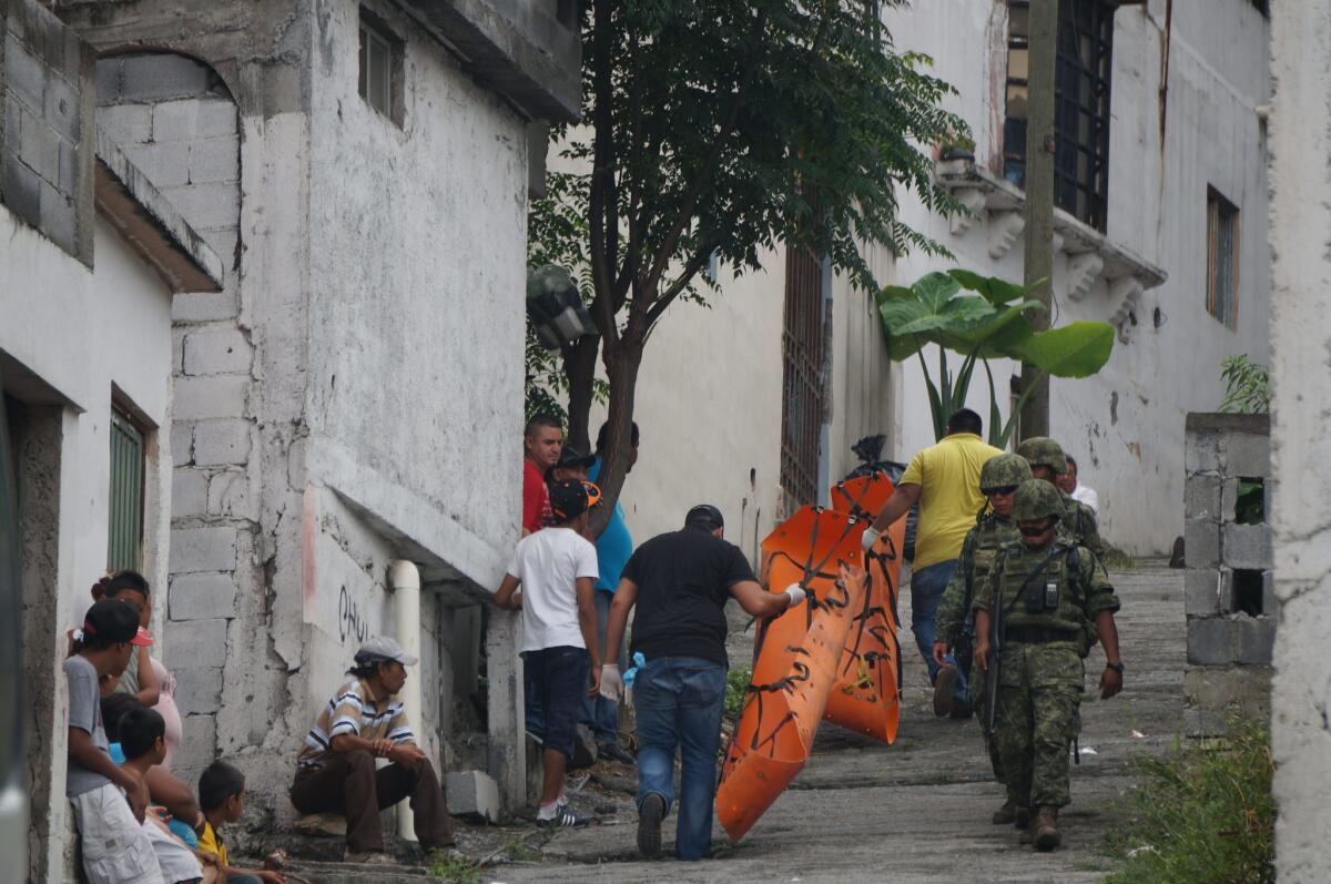 Peritos forenses llevan camillas para el levantamiento de cadáveres hoy, sábado 20 de junio de 2015, en el lugar donde tres mujeres y un hombre fueron asesinados en un barrio popular controlado por la delincuencia organizada en Monterrey, capital del norteño estado mexicano de Nuevo León, que ha sufrido una escalada de violencia al registrarse 17 asesinatos en las últimas 24 horas.